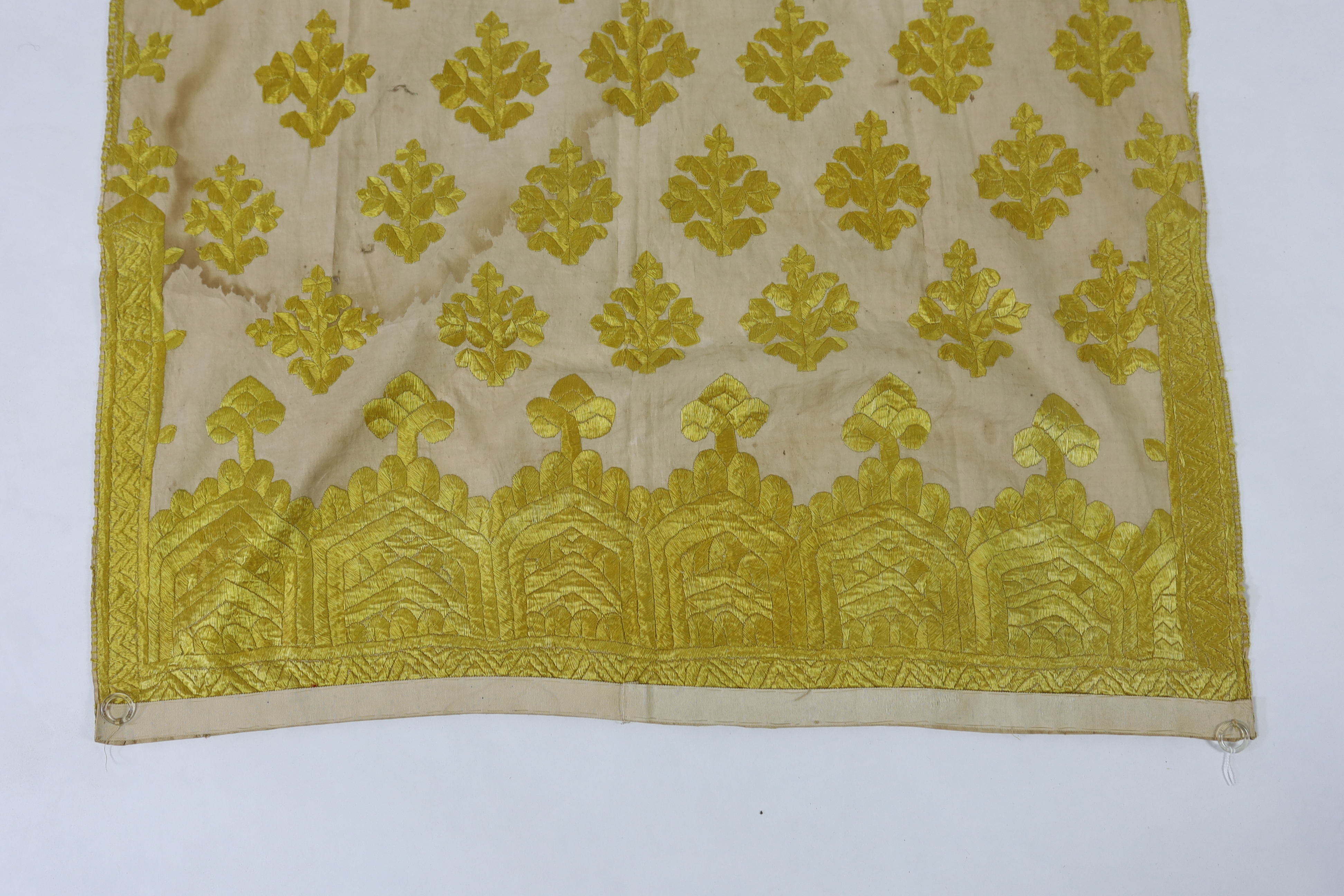 An early 20th century North Indian cotton yellow silk hand embroidered panel, with wide embroidered borders and all over stylistic spot motifs, 122 cm long x 80cm wide